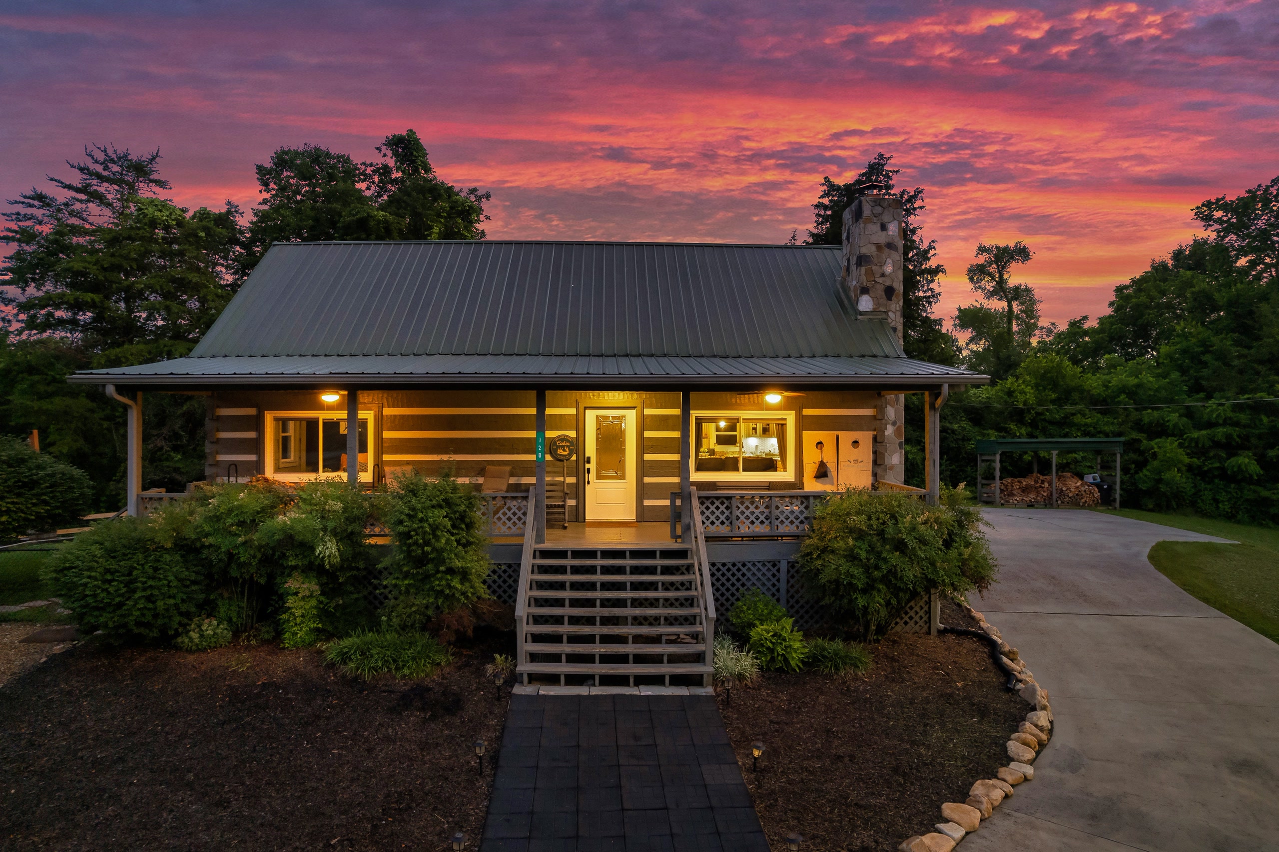 Hillside Haven cabin front view at dusk with stone chimney and metal roof in Tennessee