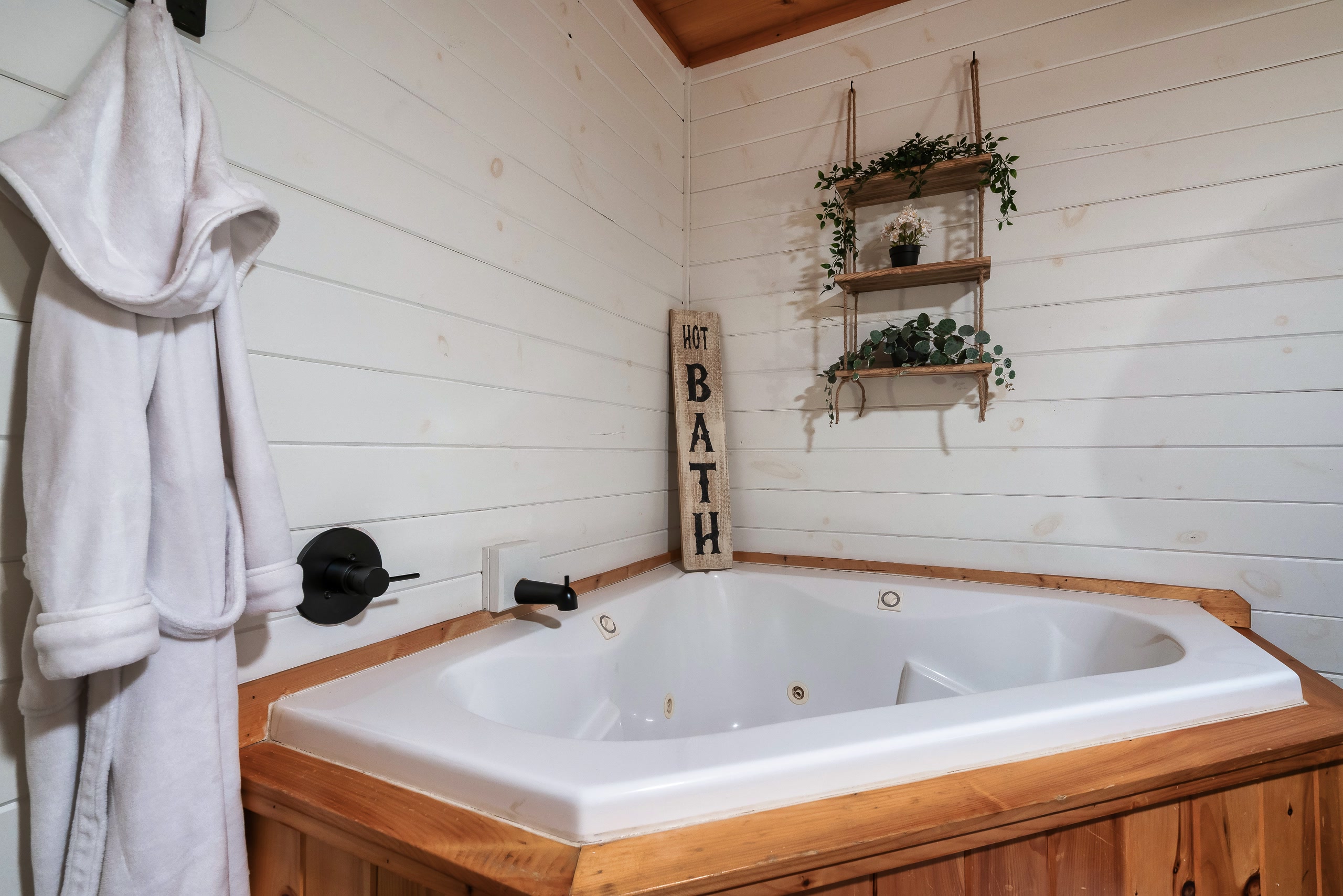 Corner jetted tub with wood trim and floating shelves at Smoky Creek Hideaway