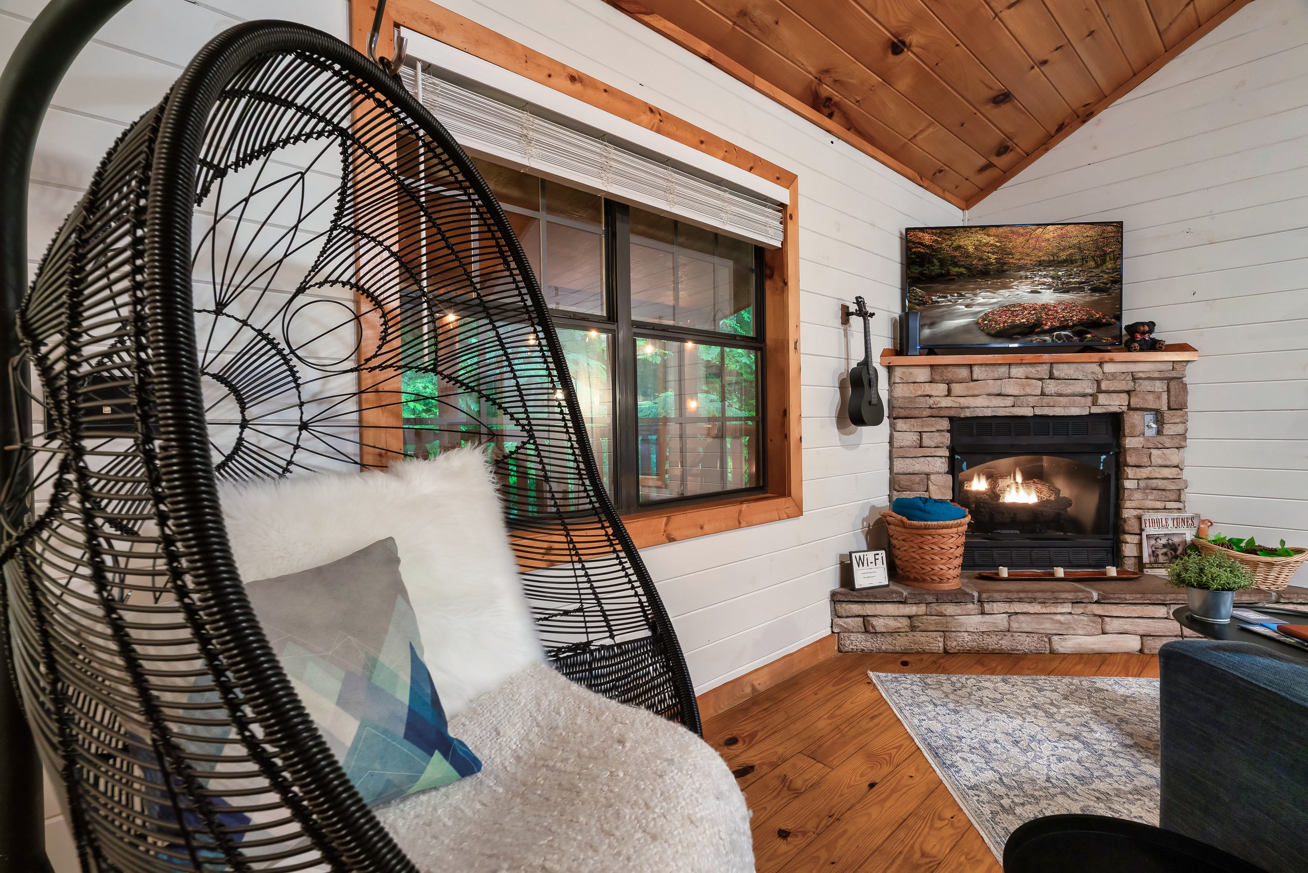 Hanging bubble chair near stone fireplace in Smoky Mountains cabin living room