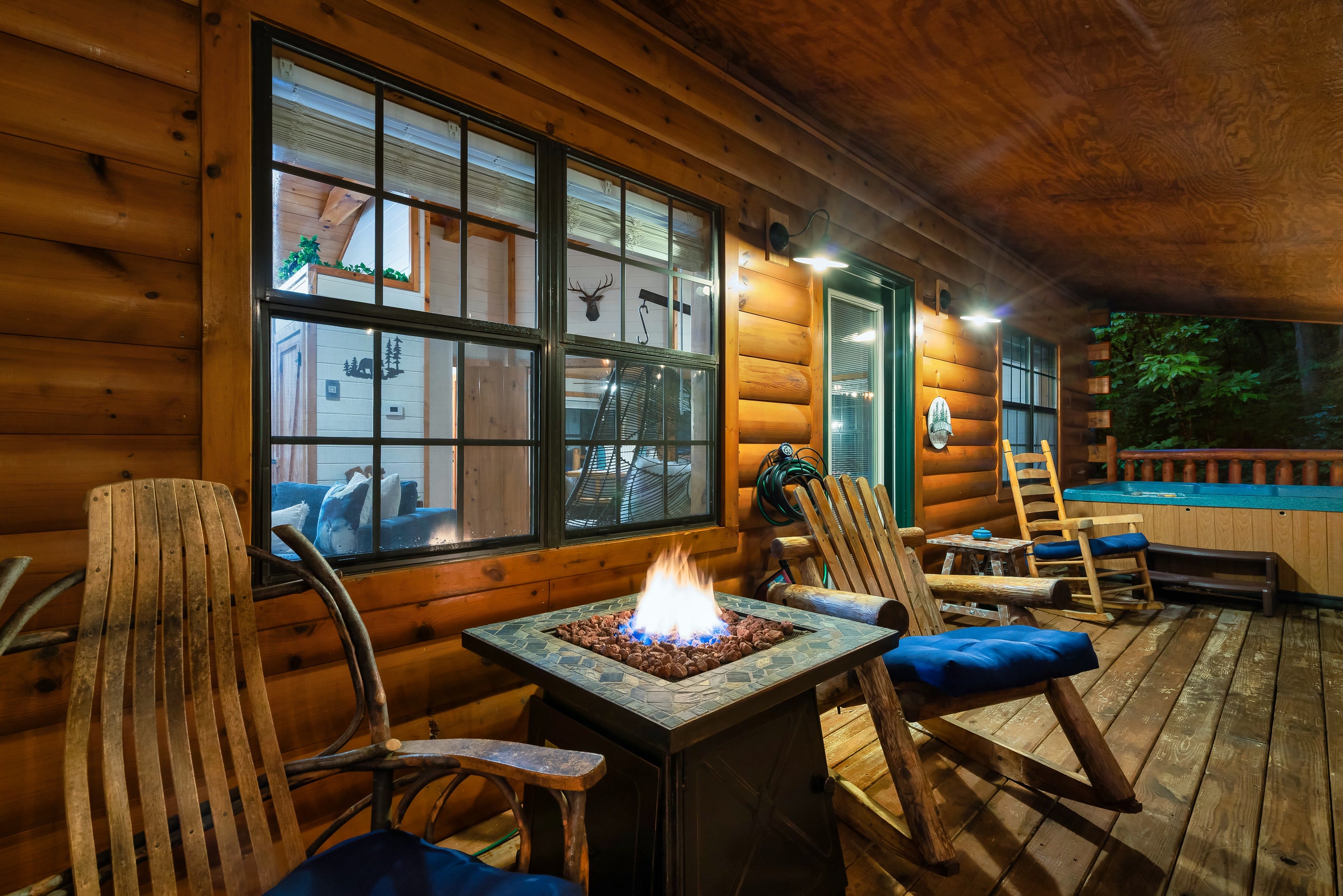 Tennessee cabin deck with hot tub, fire pit, and mountain forest views at night