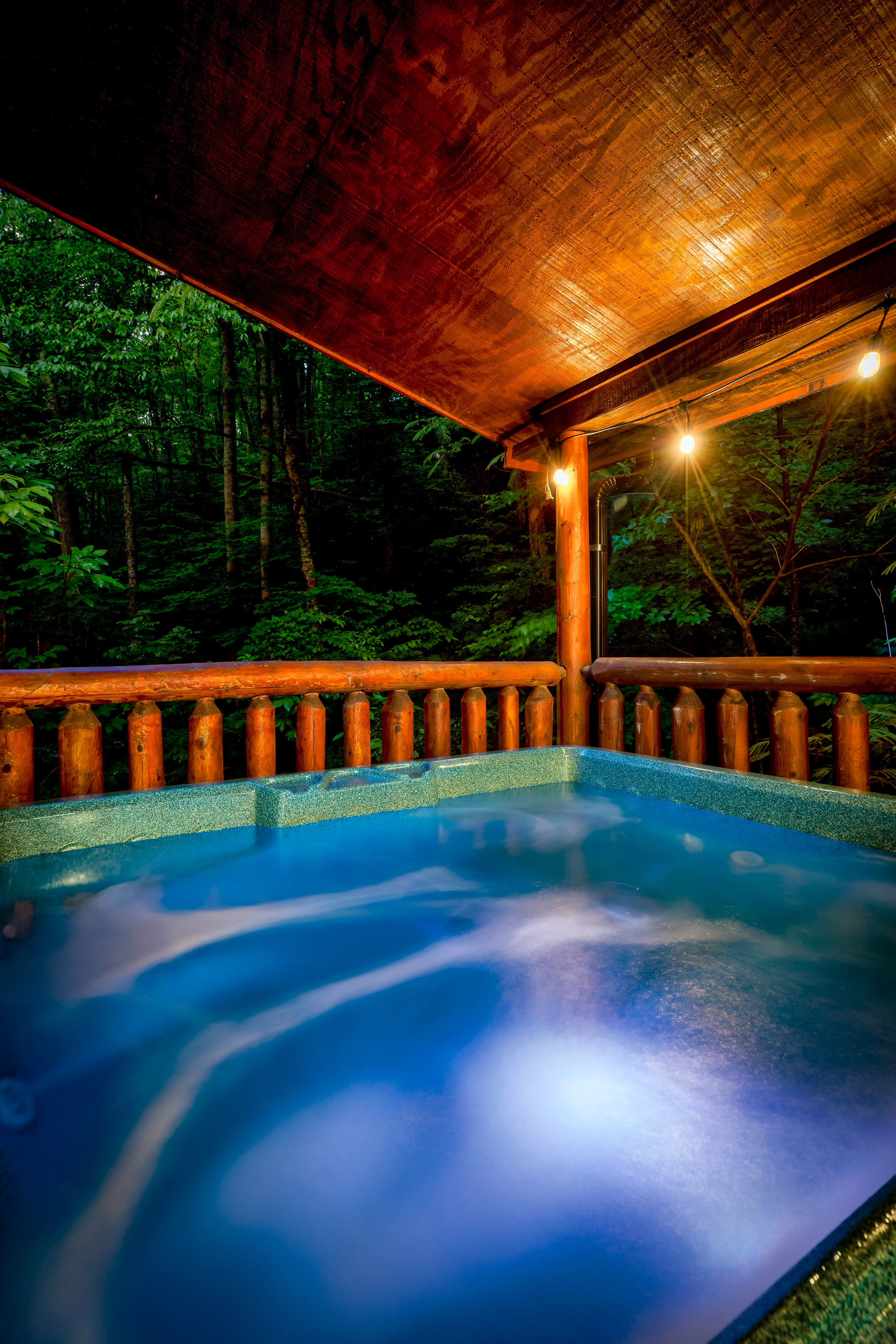 Hot tub with colored lights on Tennessee cabin deck at night