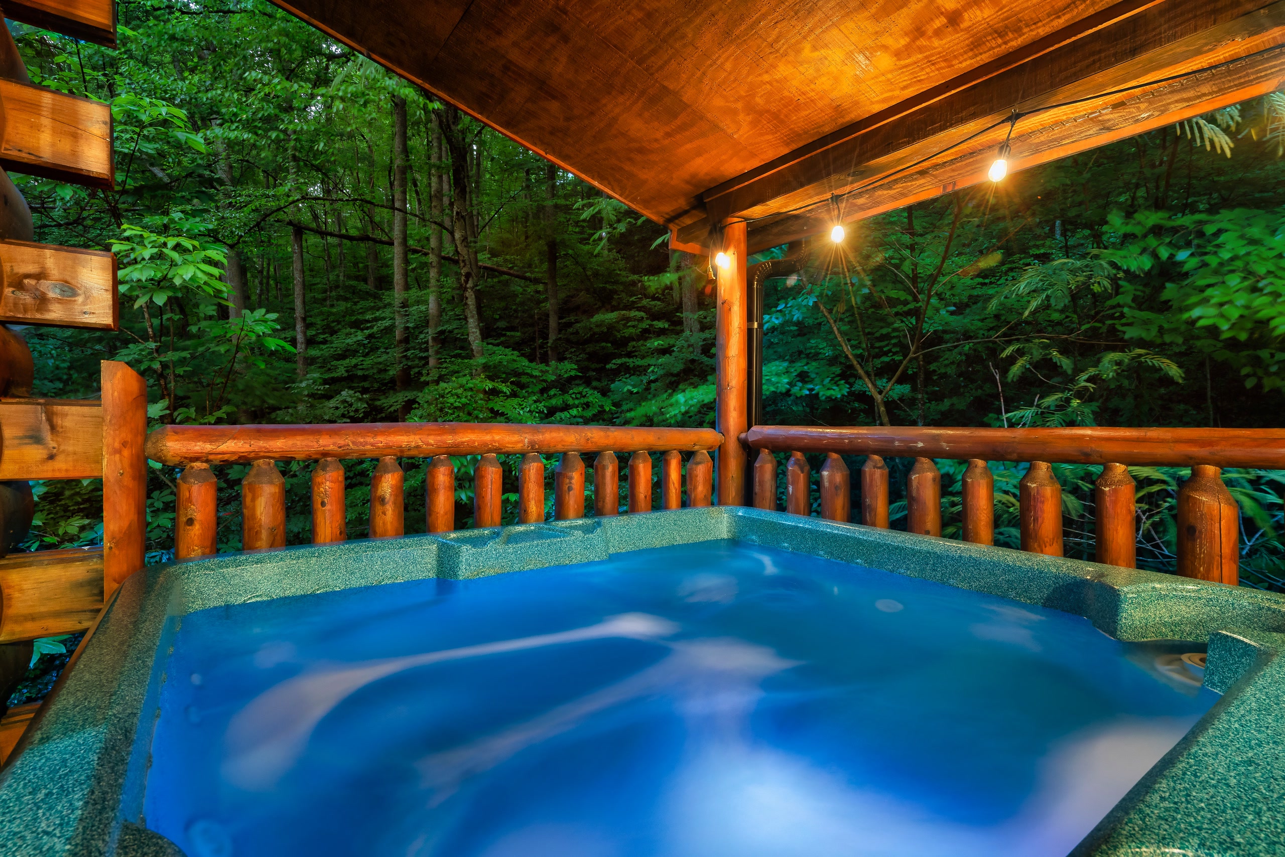 Hot tub with bubbling water on log cabin deck in Tennessee mountains at night