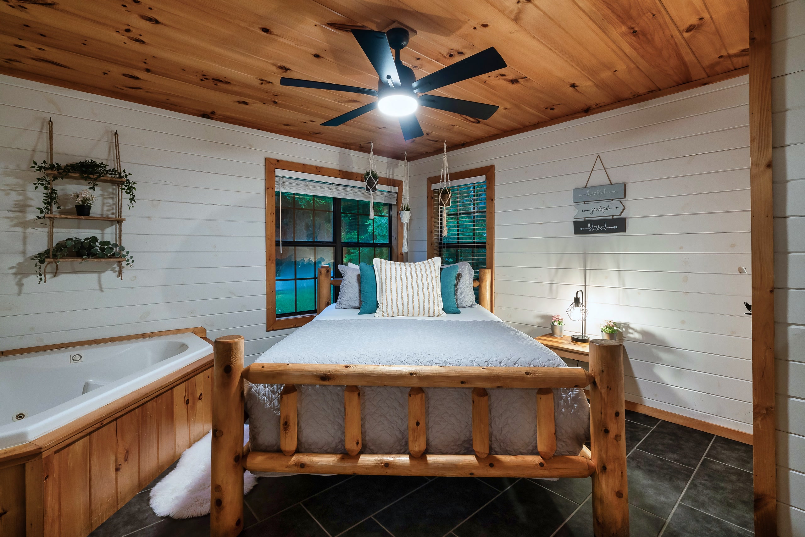 Tennessee cabin master bedroom with log bed, jetted tub, and vaulted wood ceiling