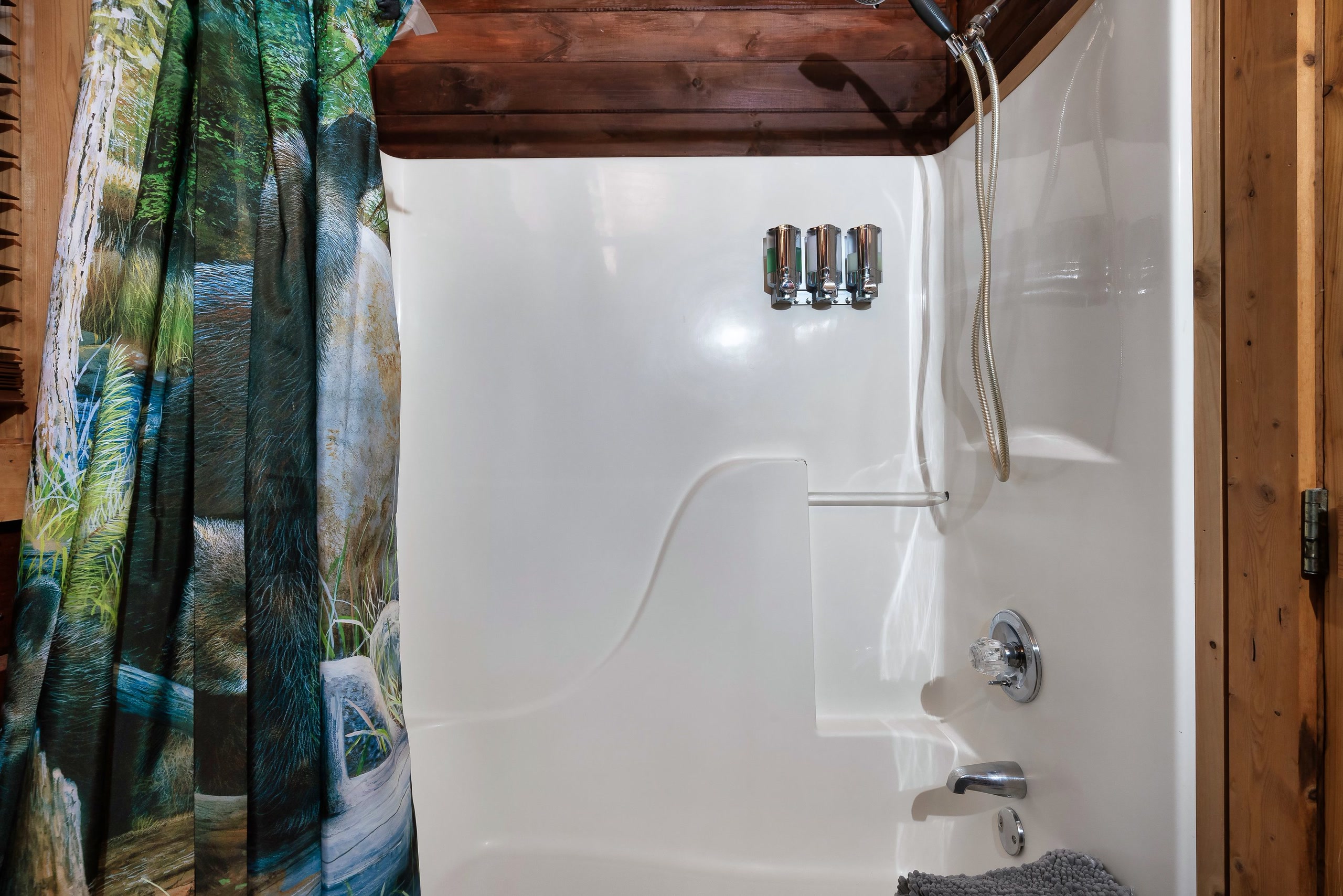 Tub-shower with forest curtain at Rustic Rooster cabin bathroom