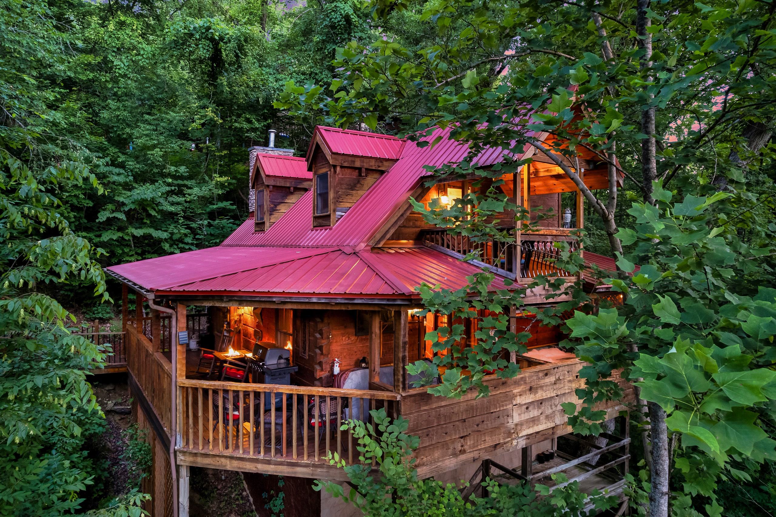 Rustic Rooster cabin exterior at twilight with red metal roof in Tennessee forest